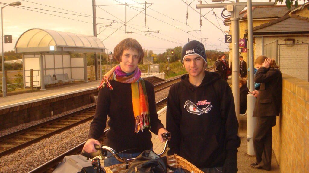 Teenage boy and girl with scarf stand on train platform