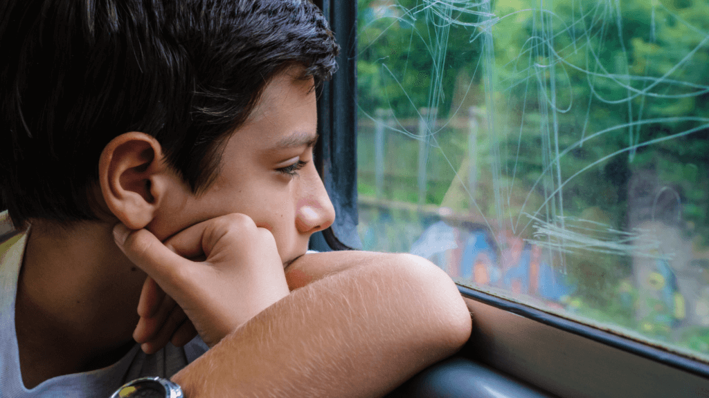 Young man with his head in hands gazing out of a train window
