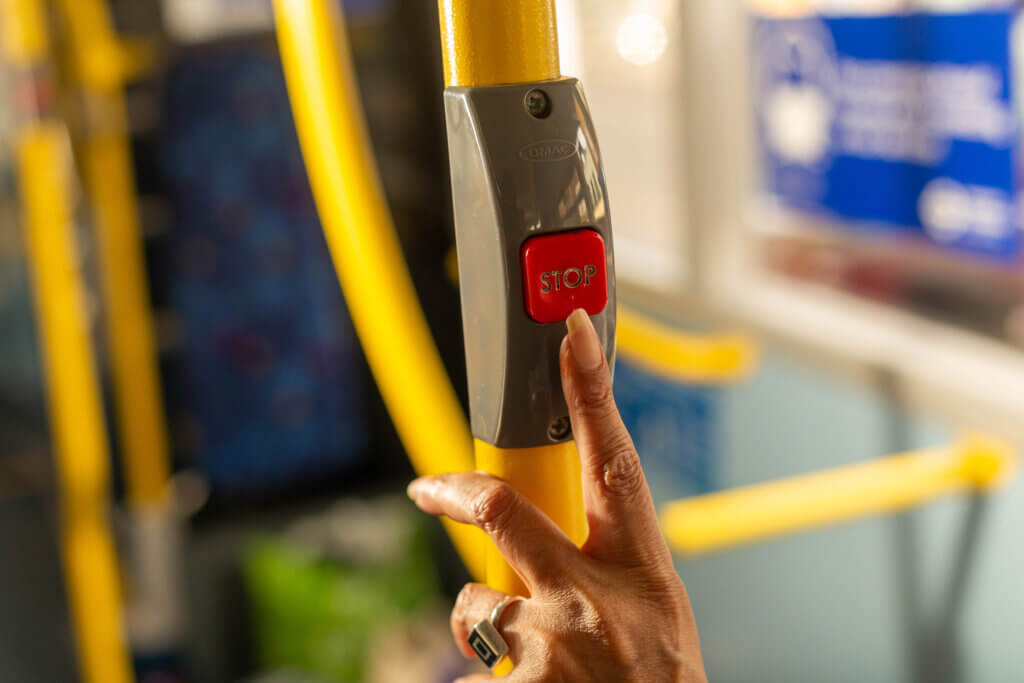 Photo: a woman's hand presses the stop button on a bus