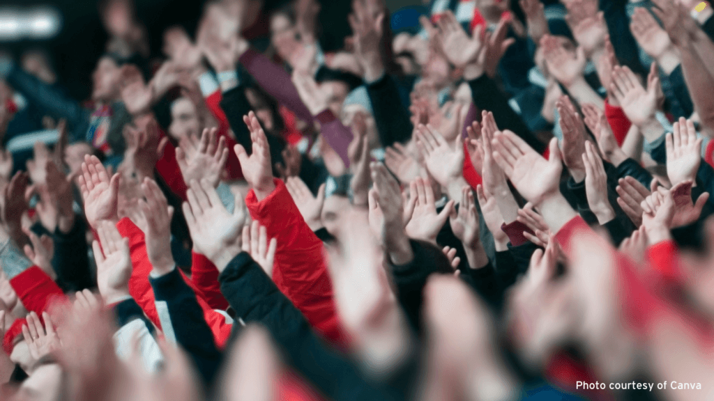 Photo of a large crowd of football fans with their arms in the air