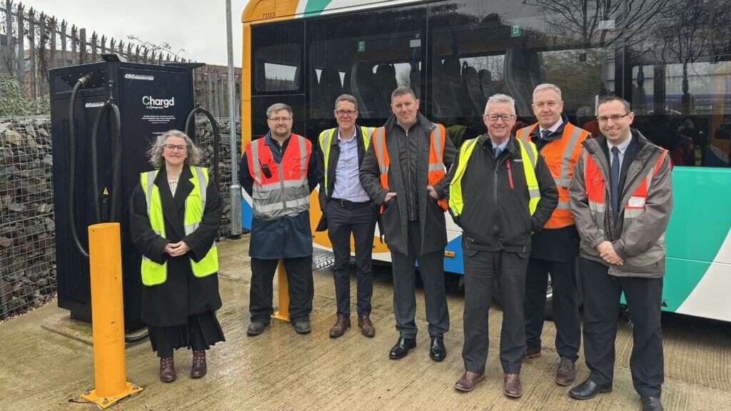 A group of people in high viz vests standing in front of an electric bus